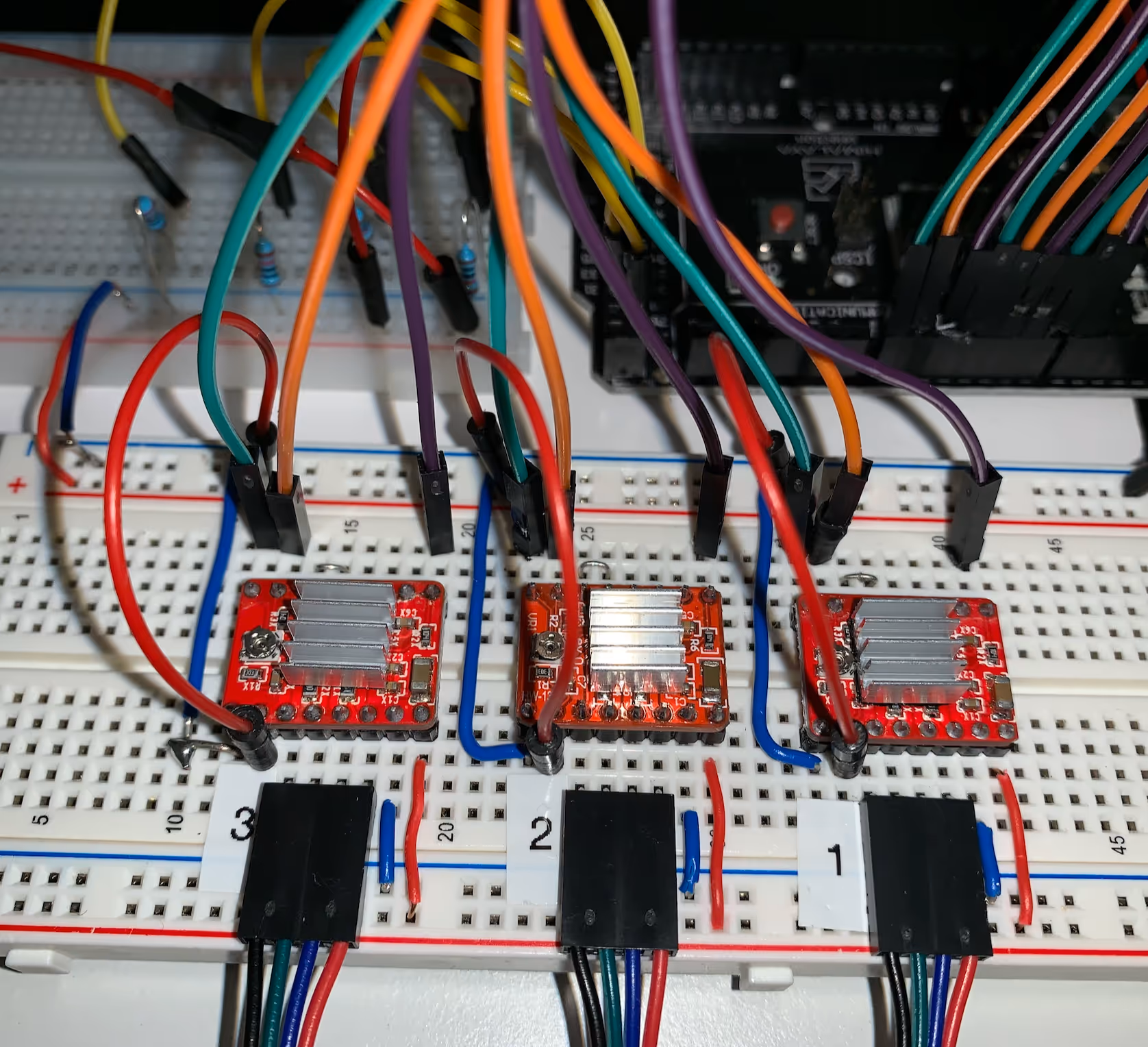 Breadboard with three stepper driver boards with heatsinks wired to an Arduino